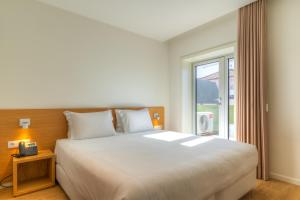 een slaapkamer met een groot wit bed en een raam bij Spot Family Apartments in Porto