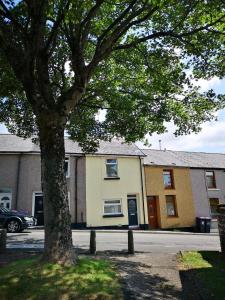 a building with a tree in front of a street at EX-MINERS COTTAGE, BLAENAVON, NEAR ABERGAVENNY in Blaenavon