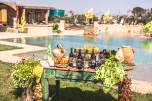 uma mesa com frutas e garrafas de vinho ao lado de uma piscina em Li Calizzi em Novoli