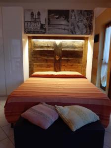 - un lit avec une tête de lit en bois et 2 oreillers dans l'établissement Le Chat Riant, à Fenis