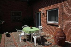 a patio with a table and chairs and a brick wall at Ferienhof Friedenshof Hafer in Vollerwiek