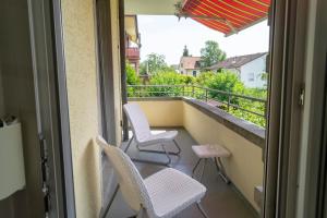 a balcony with two chairs and a table and an umbrella at Luegete 28, Witikon Apartments in Zürich