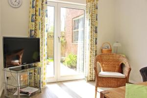 a living room with a tv and a sliding glass door at Ferienhof Friedenshof Hafer in Vollerwiek