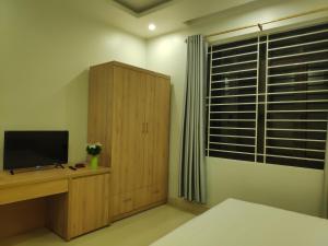 Schlafzimmer mit einem TV und einem Holzschrank in der Unterkunft Latte Motel in Dong Hoi
