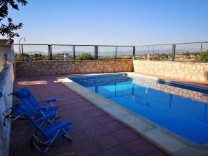 a swimming pool with two blue chairs next to it at Casa Rural Carricola in Carrícola