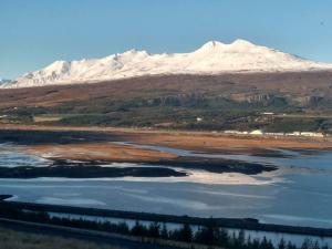 a snow covered mountain with a body of water at Hafdals Hotel in Akureyri
