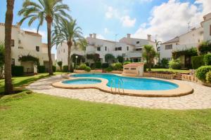 een zwembad in een tuin met palmbomen en gebouwen bij Las Moras II UL by CARLOSFERIEN in Denia