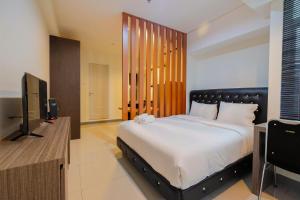 a bedroom with a large bed and a flat screen tv at Elegant 1BR at Grand Kamala Lagoon Apartment By Travelio in Pekayon Satu