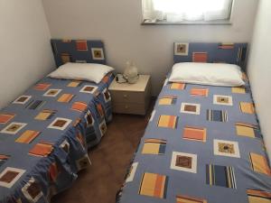 a bedroom with two beds and a nightstand with two beds at Platamona Villaggio Grigio in Sorso