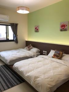 two beds in a room with green walls at Warm B&B in Magong