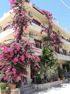 un edificio con flores rosas delante de él en Knossos Hotel, en Kalamaki