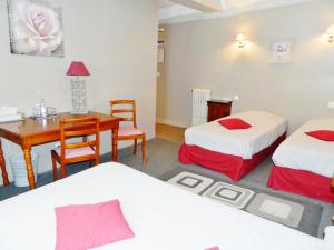 um quarto com 2 camas, uma secretária e uma mesa em Hotel Restaurant Le Cygne em Conches-en-Ouche