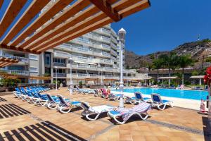 a row of lounge chairs next to a swimming pool at Apartamento Ocean View in Puerto de Santiago