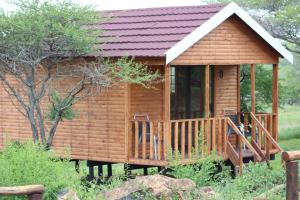 a wooden cabin with a porch and two chairs at Igula lodge in Mkuze