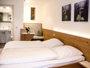 a bedroom with two white beds and a kitchen at Gästehaus am Westtor in Prichsenstadt