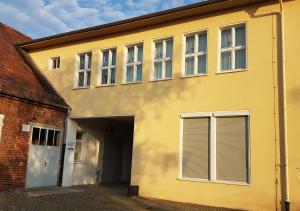 a yellow building with windows and a garage at Hostel jo-si in Kamenz