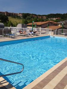 a large blue swimming pool with people sitting in chairs at Hotel President in Chianciano Terme
