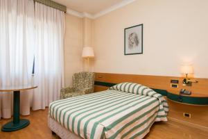una camera d'albergo con letto e sedia di Hotel San Francesco a Rende