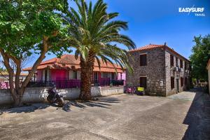 a house with a palm tree and a building at Stone House Limnos in Repanídhion