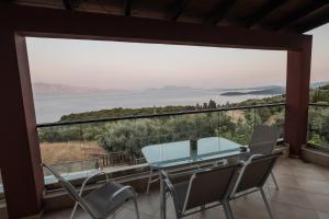 einen Blick vom Balkon eines Hauses mit einem Glastisch und Stühlen in der Unterkunft Ionion Fos in Nikiana