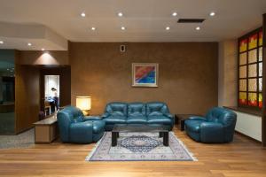 sala de estar con mesa y muebles de cuero azul en Hotel San Francesco en Rende