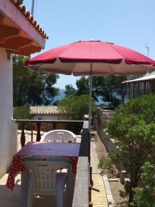una mesa con sombrilla roja y 2 sillas blancas en Villa "Maritima" en SantʼAndrea