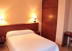 a bedroom with a white bed and a wooden headboard at Hotel Maycar in A Coruña