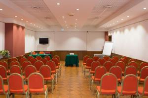 uma sala de conferências com cadeiras vermelhas e um pódio em Hotel San Francesco em Rende