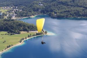 a person riding a yellow parachute over a body of water at Apartments Na Vasi in Bohinj