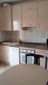 a kitchen with white cabinets and a table in it at Las Terassas- Playa de las americas - Ténérife- Espagne in Playa de las Americas