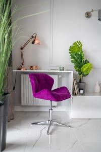 a purple chair in front of a desk with plants at Apartament MARCELIN GOLD Wes Quality Suite in Poznań