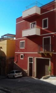 a red building with a car parked in front of it at Casa Vacanze Maniscalco Sciacca in Sciacca