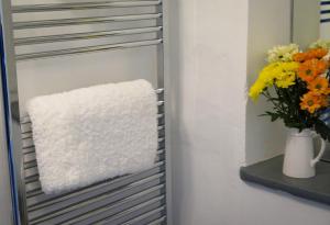 um toalheiro com um vaso de flores numa prateleira em Westeria Cottage em Barnstaple