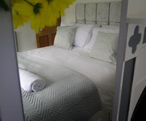 uma cama grande com lençóis brancos e almofadas em Westeria Cottage em Barnstaple