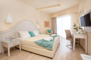 um quarto com uma cama, uma secretária e uma televisão em Pegasos Deluxe Beach Hotel em Faliraki