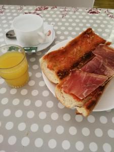 un sándwich en un plato en una mesa con una taza de zumo de naranja en Apartaments Turístics Vilaró, en Llorts