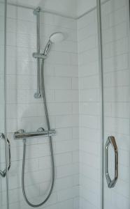 a shower with a glass shower head in a bathroom at Atpūtas Bāze Ods LOFTS in Bārta