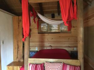 een bed in een houten kamer met rode gordijnen bij Coral in Punta Del Diablo