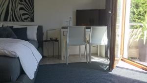 a bedroom with a bed and two white chairs at K82 BNB & Hotel in Kirchentellinsfurt