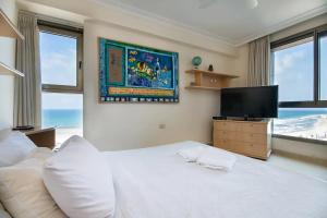 a bedroom with a white bed and a flat screen tv at Panoramic Sea-View Suite in Haifa