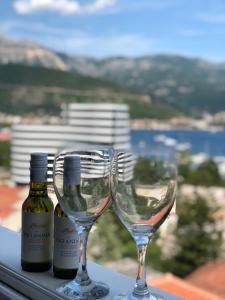 two wine glasses and bottles on a window sill at Veselinka Apartments & Rooms in Budva
