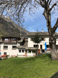 ein großes weißes Haus mit einem Baum im Hof in der Unterkunft Hotel Val d`Arca in Stampa