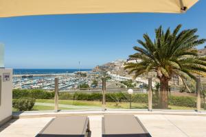 a balcony with a palm tree and a view of a harbor at Holiday Club Puerto Calma in Puerto Rico de Gran Canaria