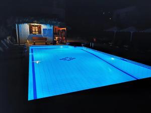 una piscina por la noche con iluminación azul en Pagaseon Rooms and Apartments en Kala Nera