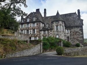 Chateau De Courbelimagne, Raulhac في Raulhac: منزل حجري قديم على تلة مع سياج