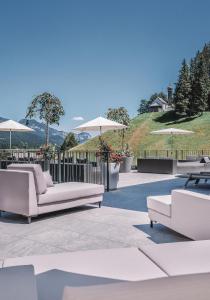 a patio with white couches and umbrellas at Das Kaiserblick 4 Sterne Superior in Ellmau