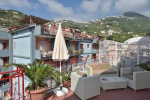 balkon z parasolem i krzesłami oraz budynek w obiekcie Costa d'Amalfi Apartments w mieście Minori