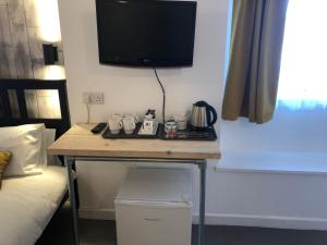 a room with a desk with a tv on the wall at Raleghs Cross Inn in Watchet