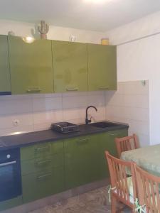 a kitchen with green cabinets and a sink and a table at Apartments Davor in Postira