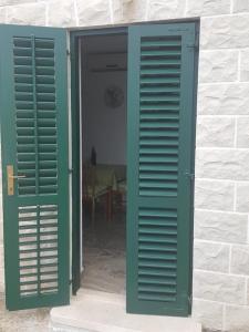 an open door with green shutters on a building at Apartments Davor in Postira